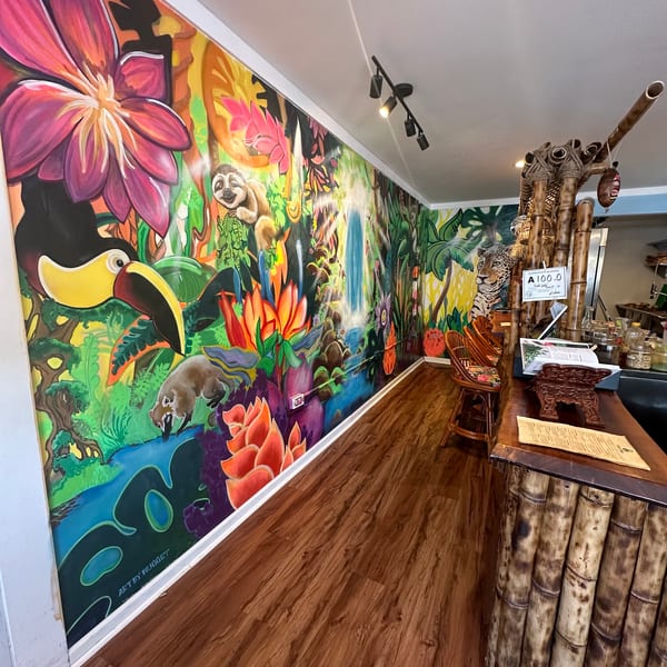 A vibrant jungle mural with animals and a waterfall, alongside a bamboo-themed counter and bar stools.