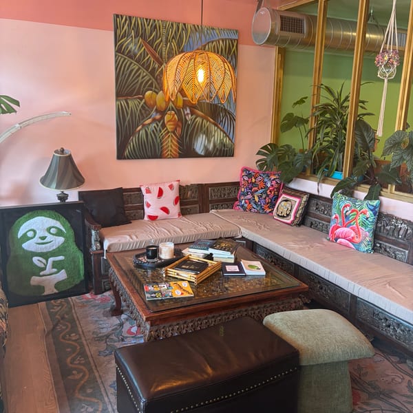Cozy, eclectic lounge area with a carved wooden sofa, coffee table, and tropical decor.